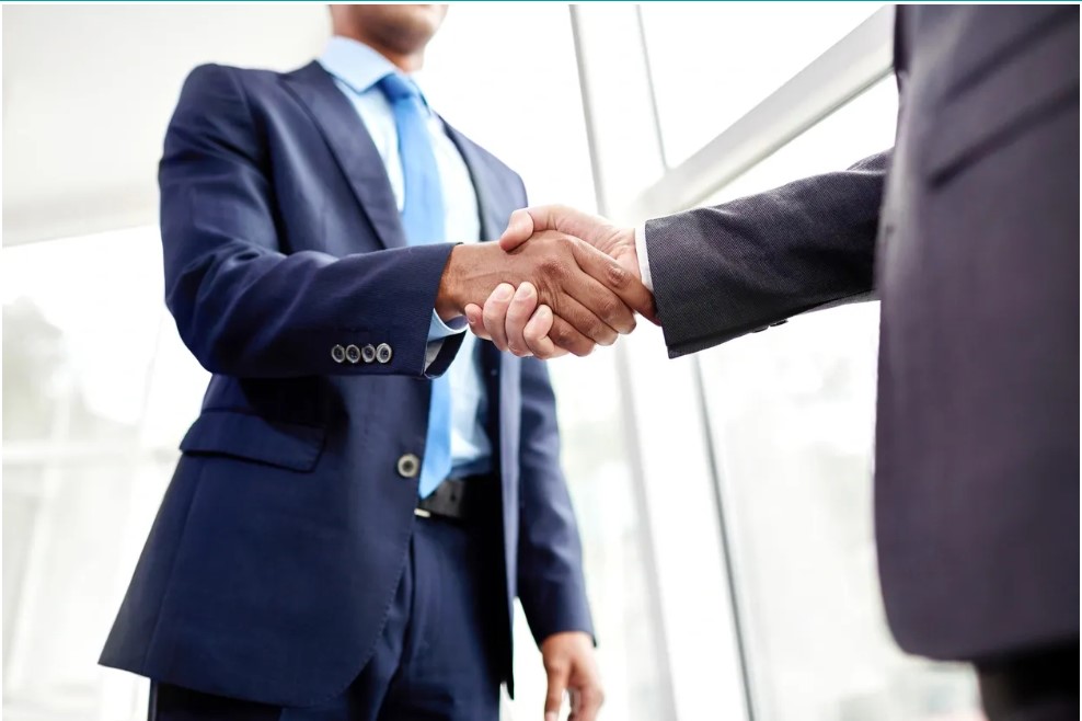 2 men in business attire shaking hands to make negotation deal